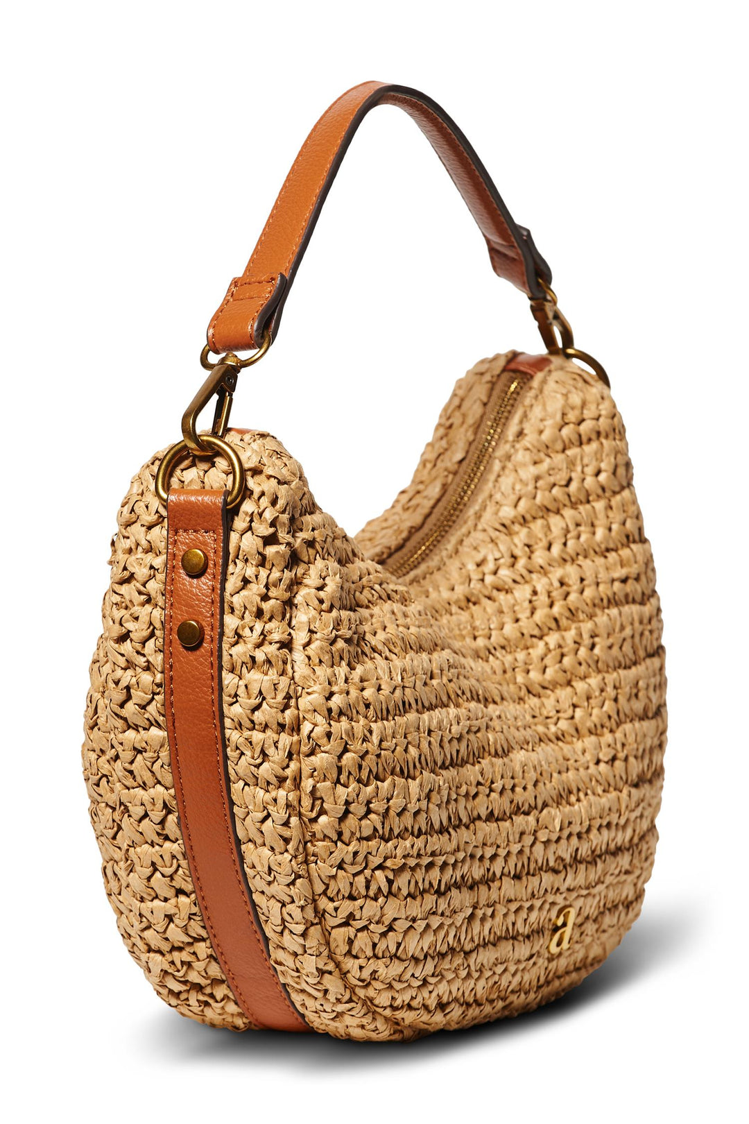 Halvmåneformet raffia skulderveske med brun lærreim og glidelås, sett fra skrå frontvinkel på hvit bakgrunn