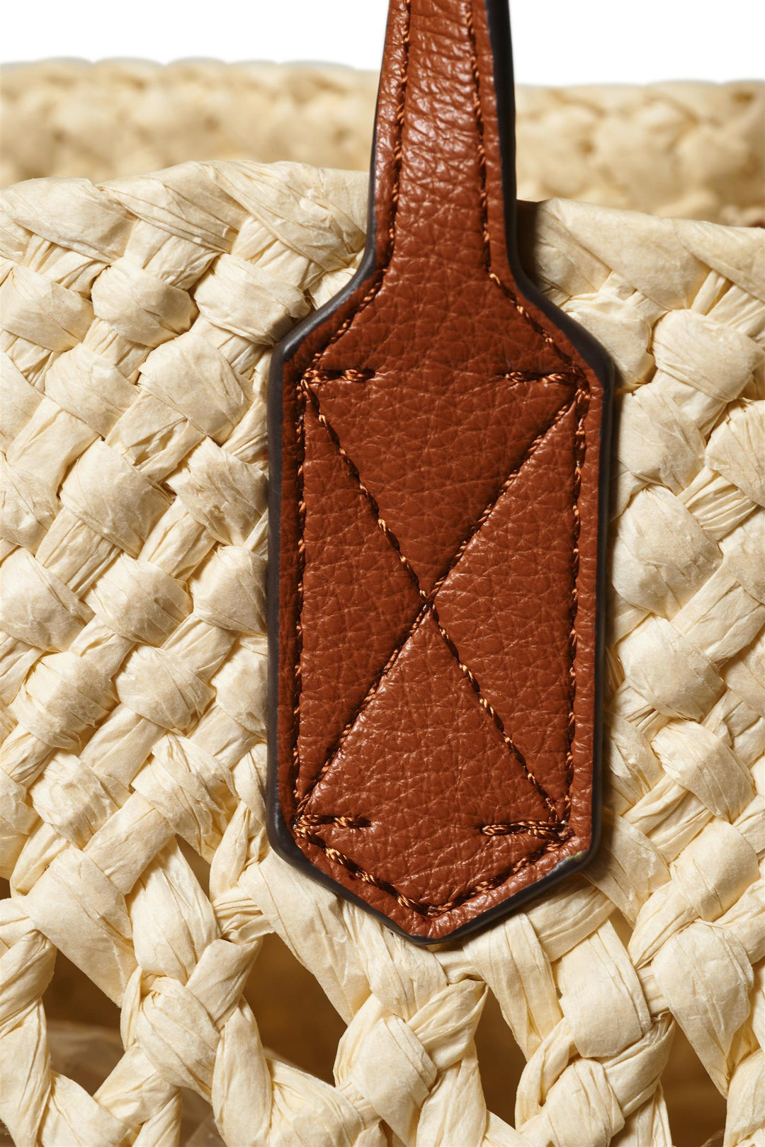 Detaljbilde av brun skinnrem med dekorativ sømdetalj på ecru strå tote-veske, ovenfra
