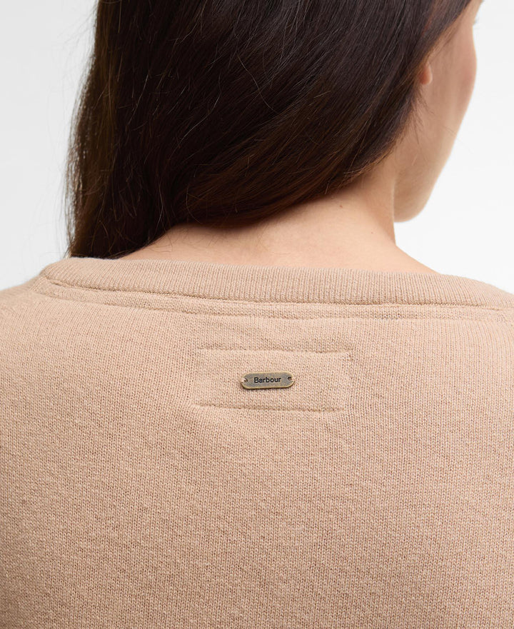 Baksiden av beige strikket genser med Barbour-merke mellom skuldrene, på modell