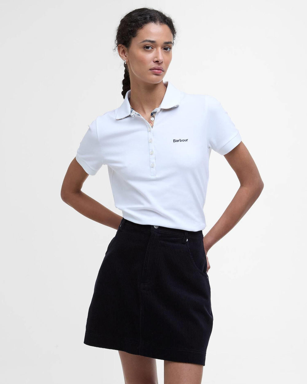 Hvit poloskjorte med Barbour-logo og rutet kragefôr, frontsett på modell med svart skjørt