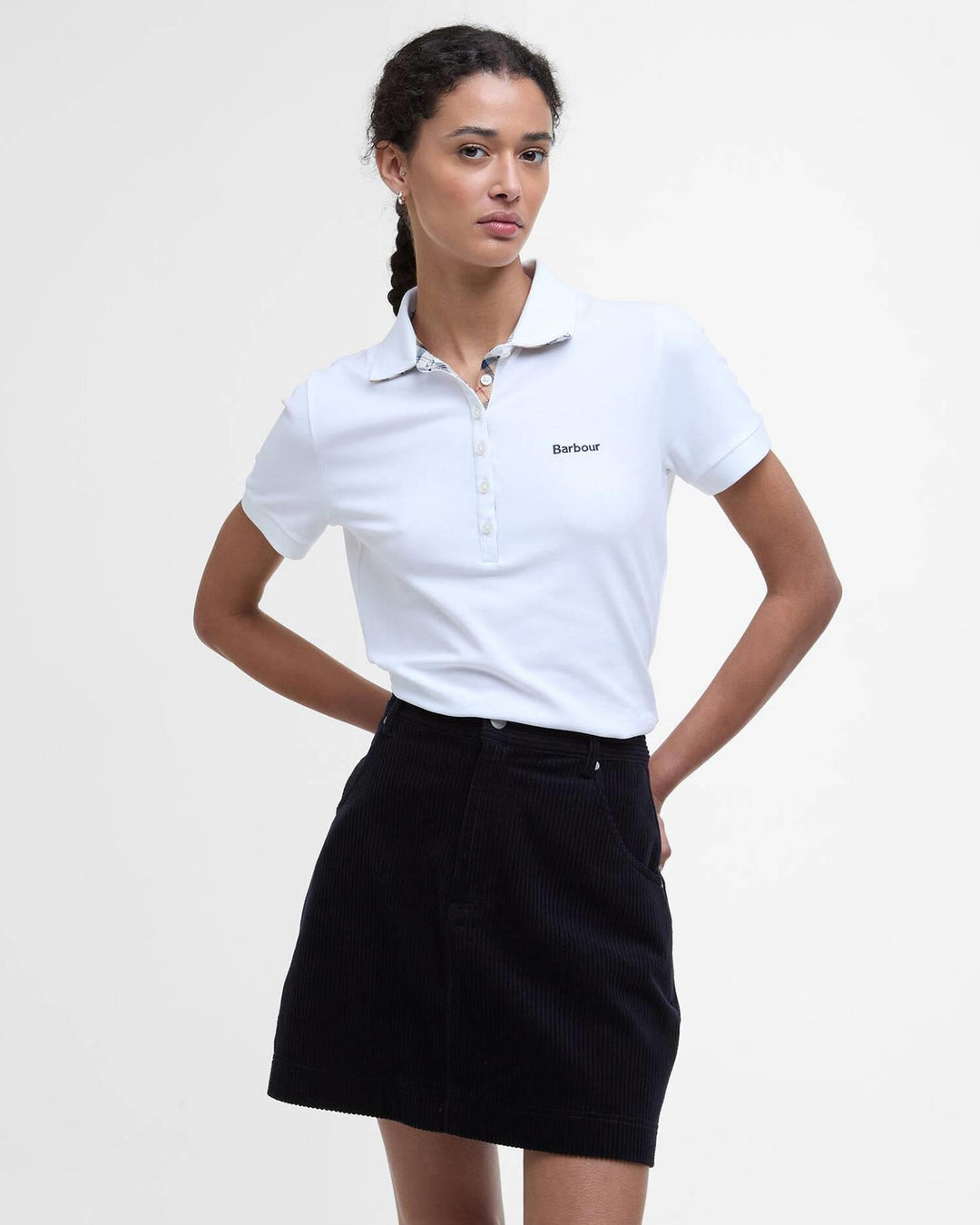 Hvit poloskjorte med Barbour-logo og rutet kragefôr, frontsett på modell med svart skjørt