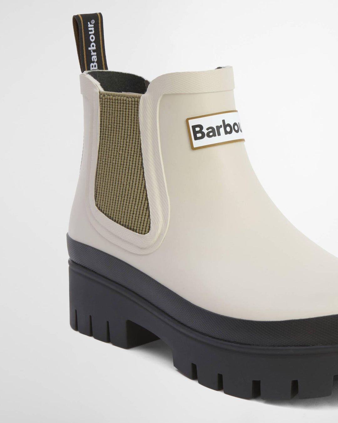 Sidevinkel av lyse ankelstøvletter med olivengrønn elastikk, Barbour-logo og profilert svart såle