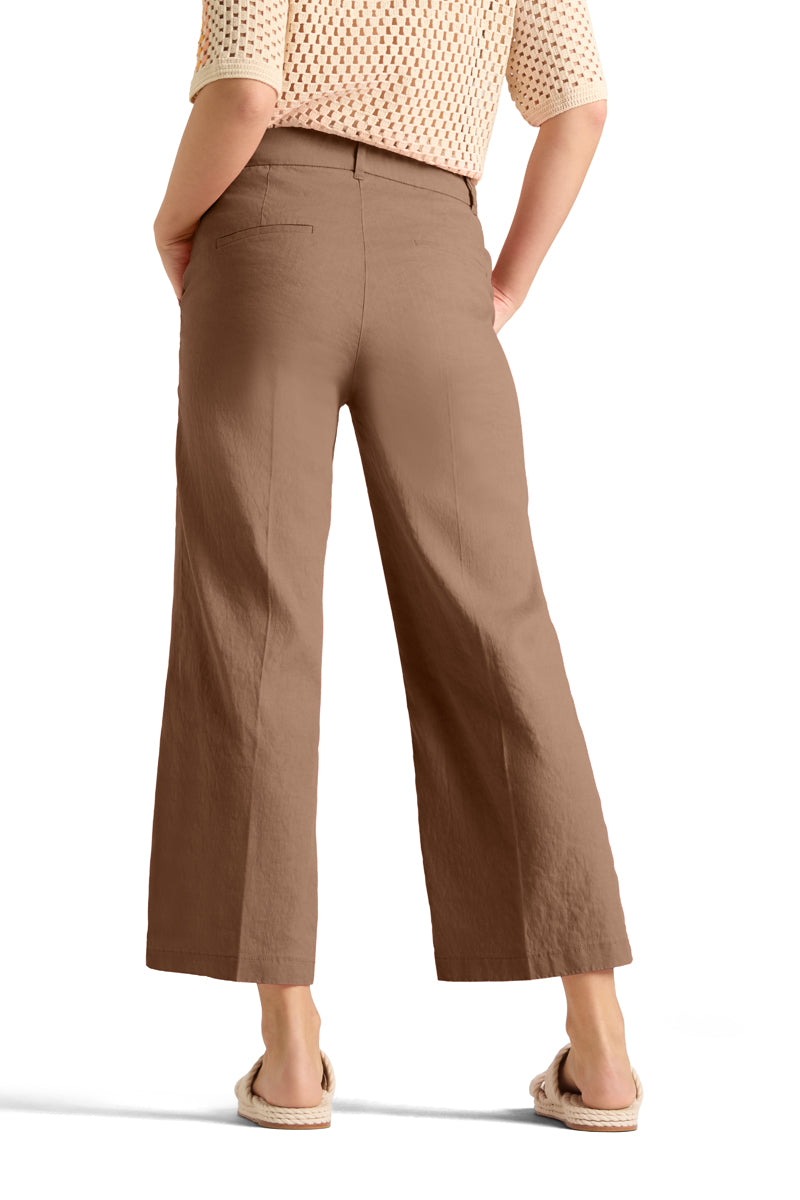 Bakside av beige bukser med vide ben, baklommer og linning, modell i espadrillos