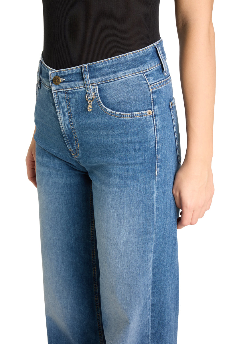Nærbilde av høy linning med metallknapp, lommekjede og kontrastsøm på medium blå jeans