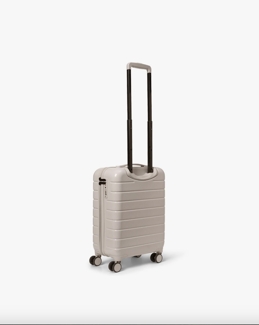 Pastel beige hardskall kabinkoffert med teleskophåndtak utstrakt, sidevinkel med fire hjul synlig