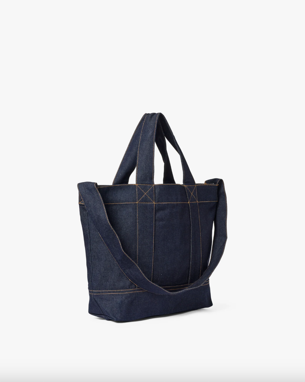 Mørk denim tote-veske med crossbody-rem og kontrastsømmer, sidevinkel mot hvit bakgrunn