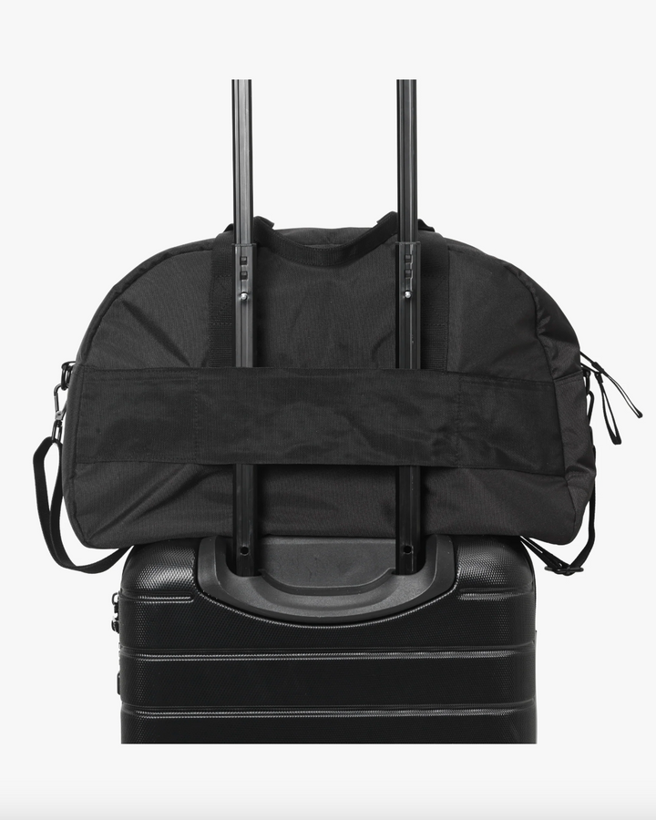 Svart duffelbag festet til koffert med trolley-stropper, frontsett med doble håndtak og skulderrem