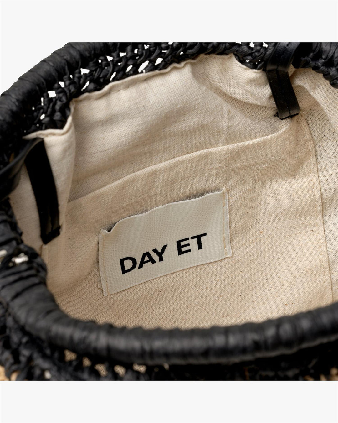 Innvendig detaljbilde av clutch med naturfarget fôr og DAY ET merkelapp i lomme