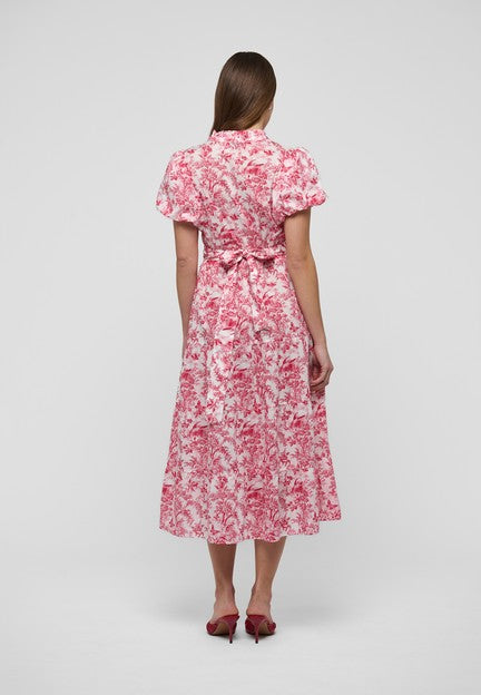 Bakside av rød og hvit blomstret kjole med bindebelte i midjen på modell