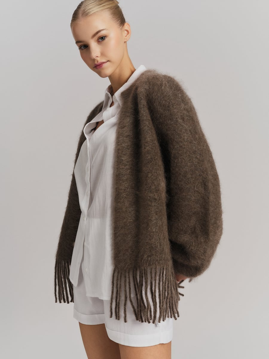 Brun chunky cardigan med frynser og belte, frontsett på modell over hvit skjorte