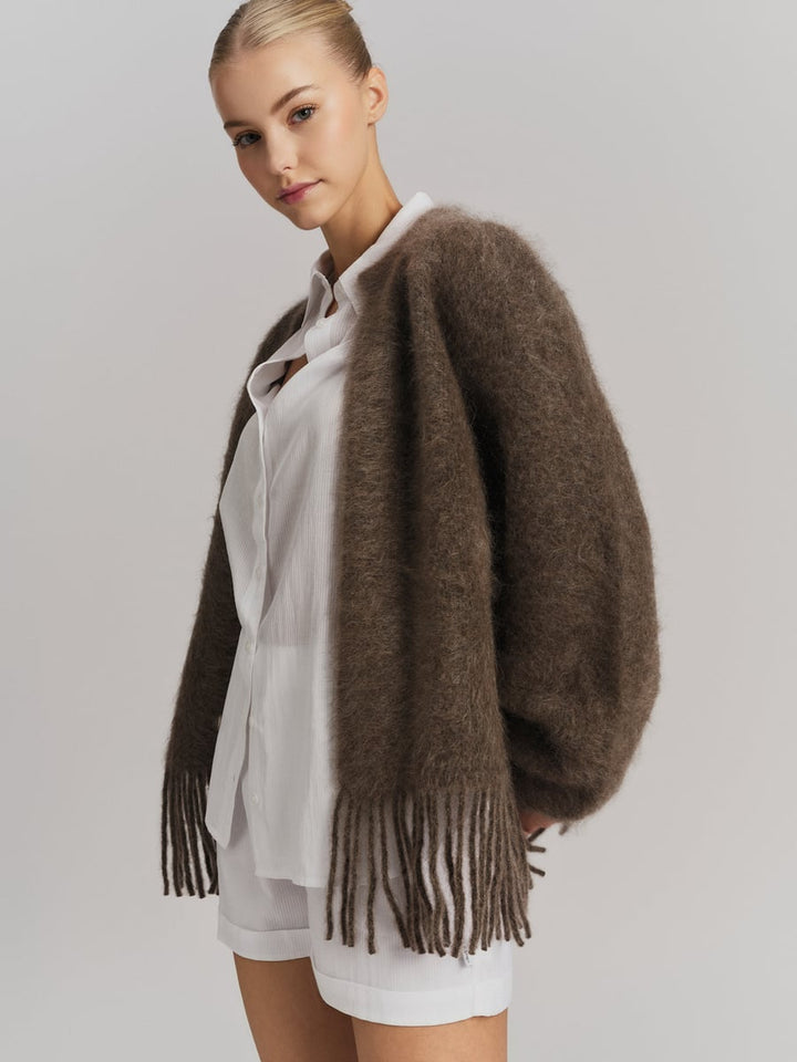 Brun chunky cardigan med frynser og belte, frontsett på modell over hvit skjorte