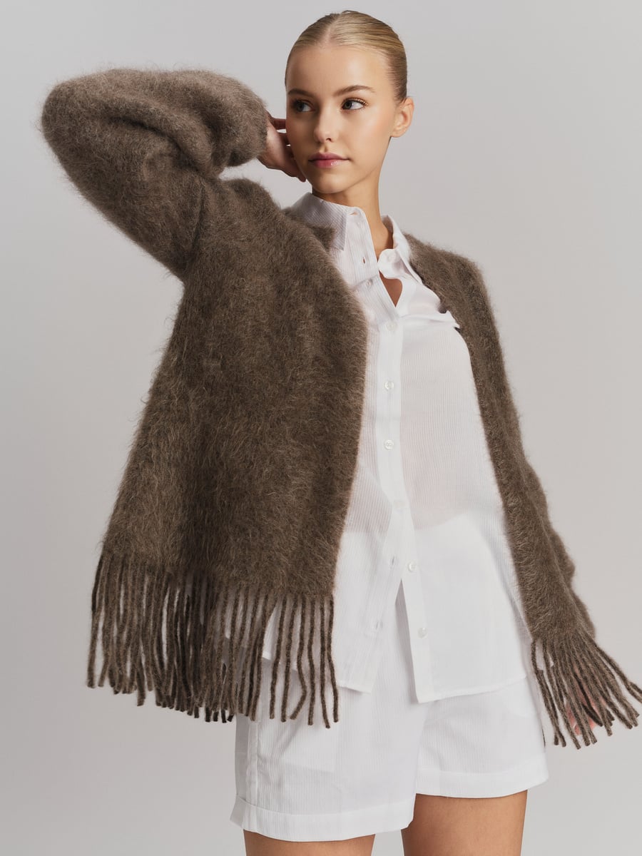 Brun chunky cardigan med frynser på modell, frontsett med åpen front over hvit skjorte