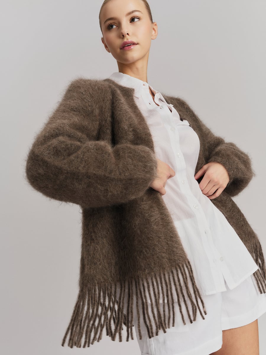 Brun chunky cardigan med frynser og belte, frontsett på modell over hvit kjole