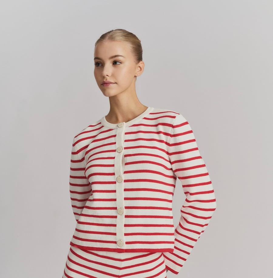 Hvit cardigan med røde striper og hvite knapper, frontsett på modell i studio