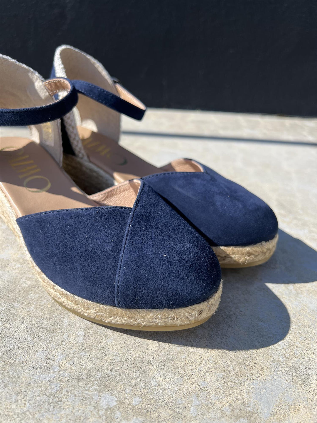 Marineblå espadrille kilehæl sandaler med ankelrem, sidevinkel på betongunderlag i sollys