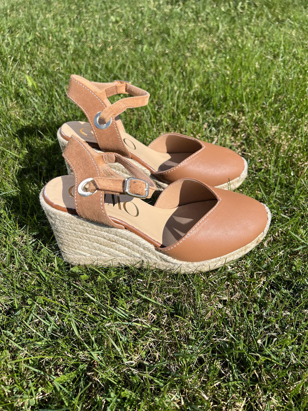 Brune espadrille kilehæl sandaler med lukket tå og ankelrem, sidevinkel på gressbakgrunn