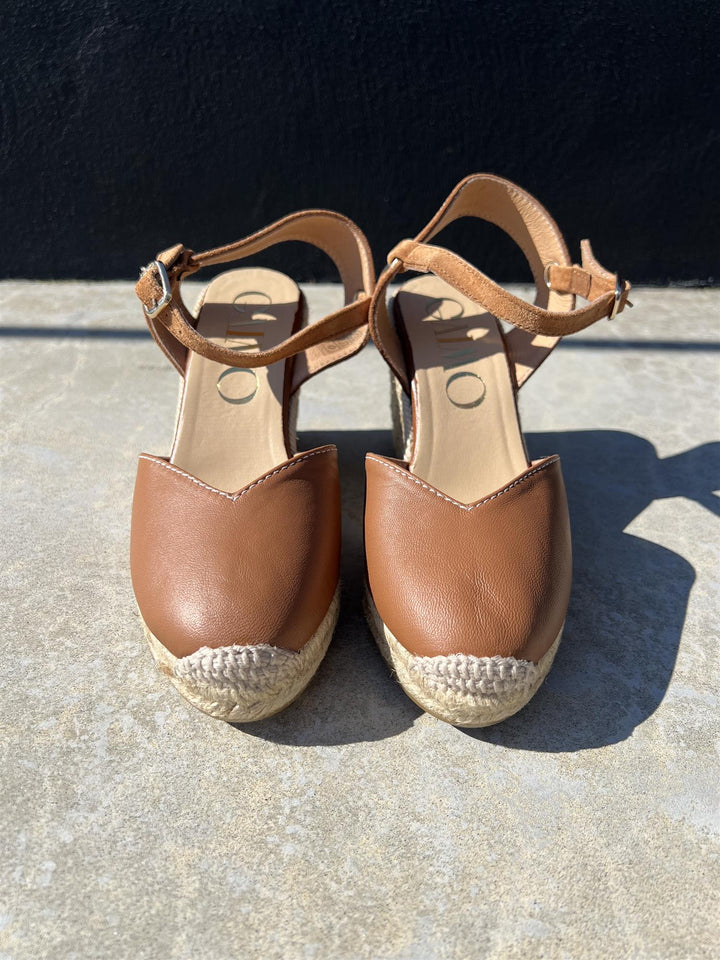 Brune espadrille kilehæl sandaler med ankelrem og jutefletting, frontsett på grå bakgrunn i sollys