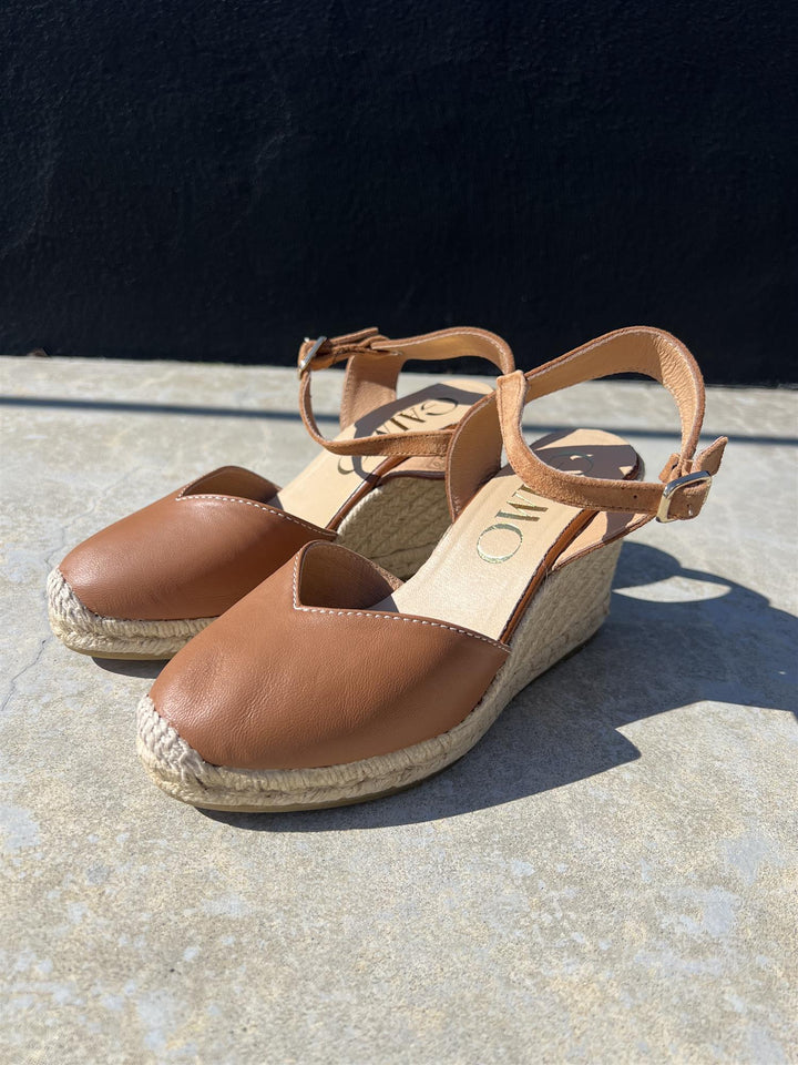 Brune espadrille kilehæl sandaler med ankelrem og jute såle, sidevinkel på betonggulv i sollys
