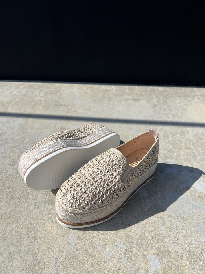 Heklede espadriller med platåsåle i naturfarget tekstil, sidevinkel på steingulv i sollys