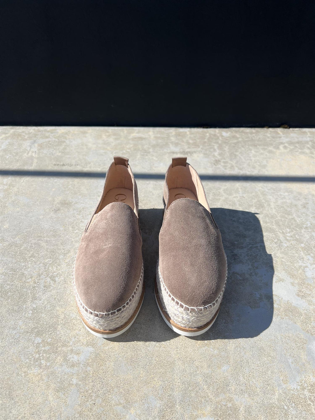 Taupe espadrillesko med jute-såle og pull-tab, frontsett på solbelyst steinfliser utendørs