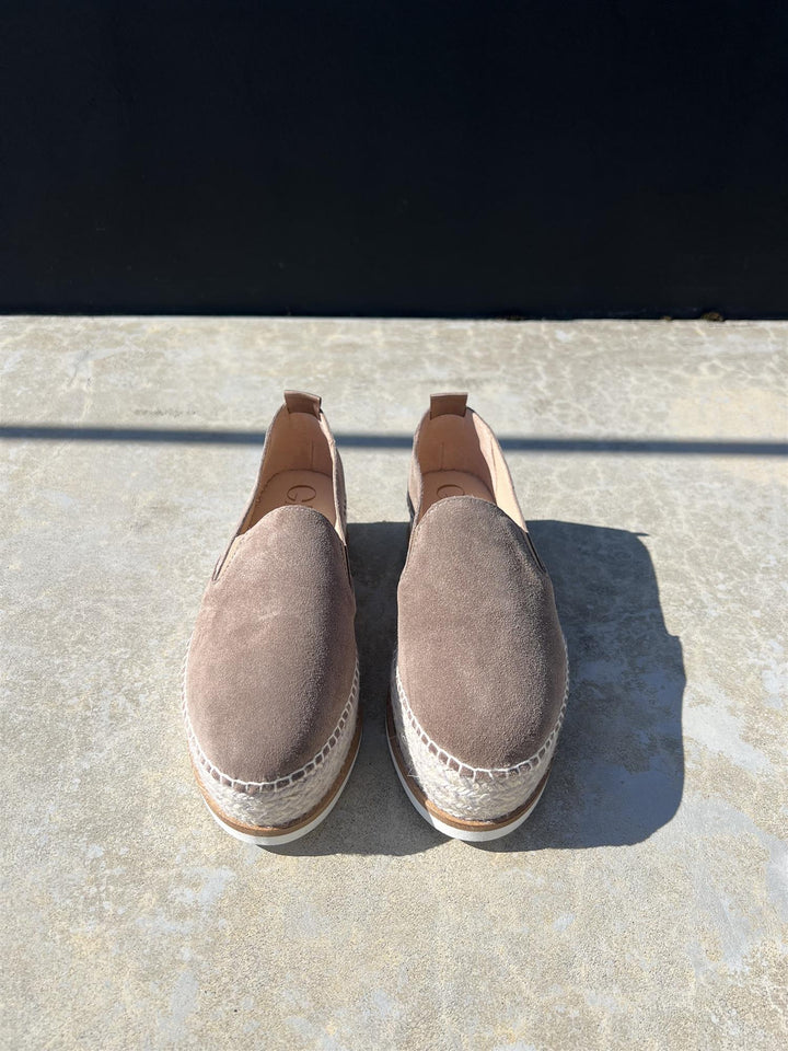 Taupe espadrillesko med jute-såle og pull-tab, frontsett på solbelyst steinfliser utendørs