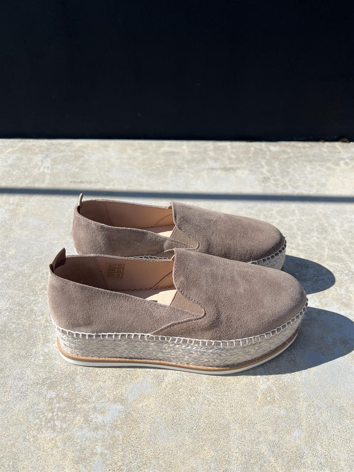 Taupe espadrilles med jute-såle og hvit gummibunn, sidevinkel på steinfliser i sollys