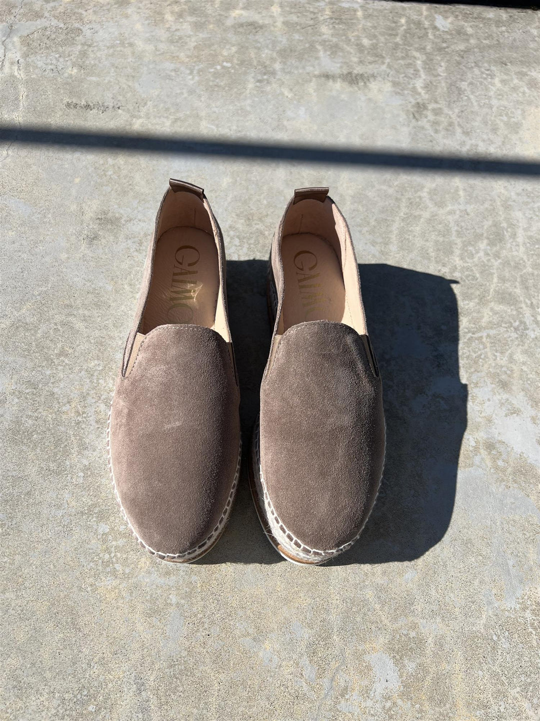 Taupe espadrilles med semsket overdel og jute-såle, ovenfra på betongunderlag i sollys