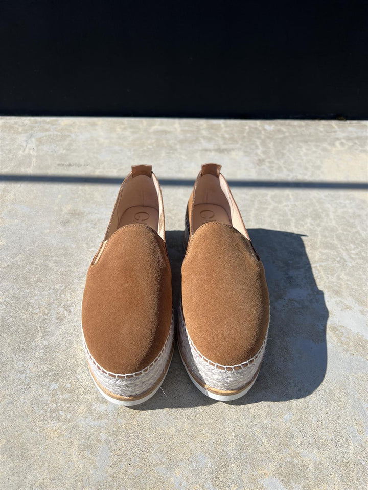 Brune espadrille slip-on sko i semsket skinn, frontsett på steinfliser i sollys
