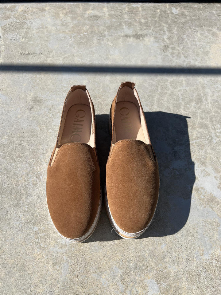 Brune espadrille slip-on sko i semsket skinn, ovenfra på betongunderlag i sollys