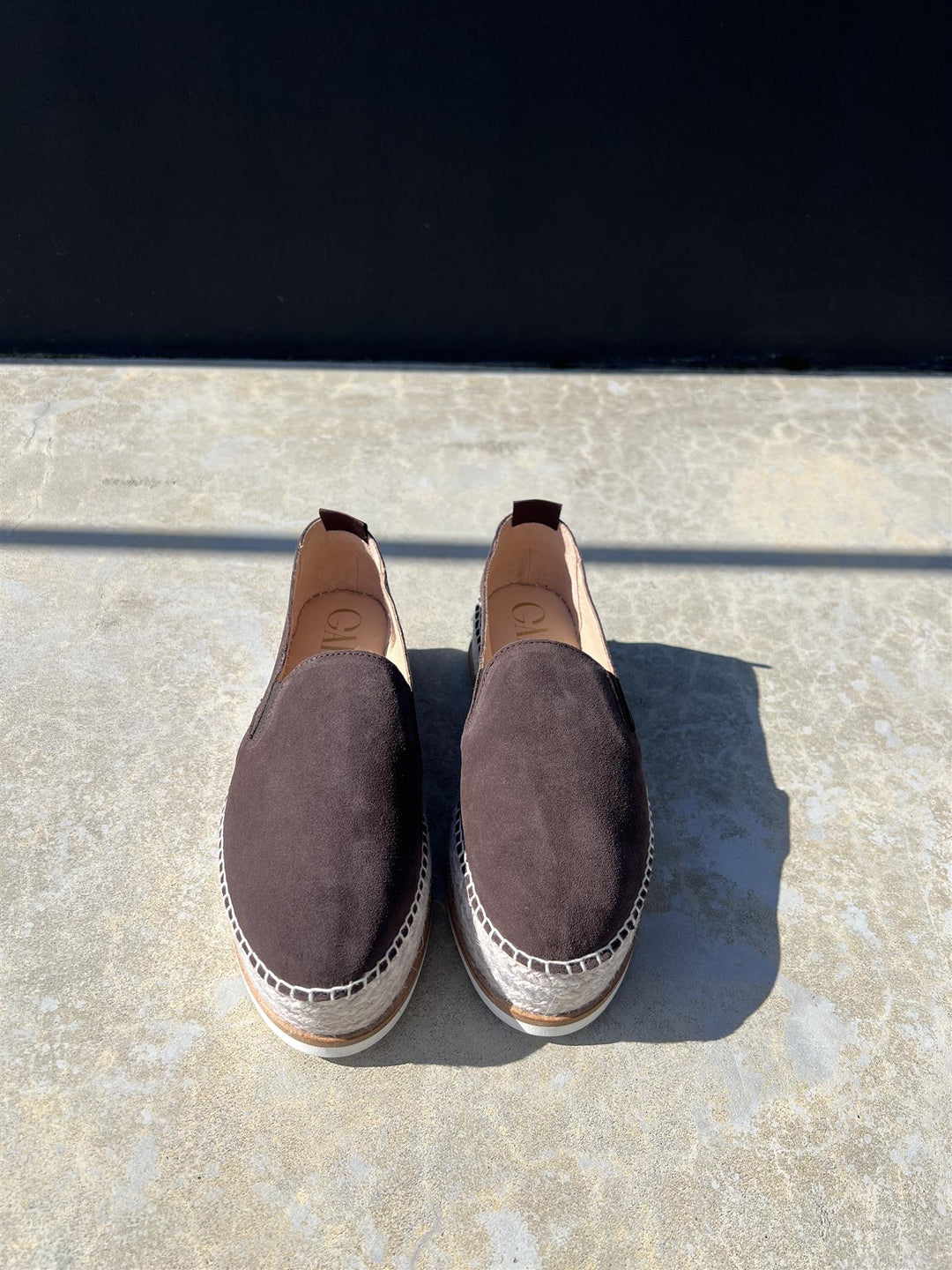 Chokoladebrun espadrille slip-on sko med platåsåle og jutetau, frontsett på steingulv i sollys