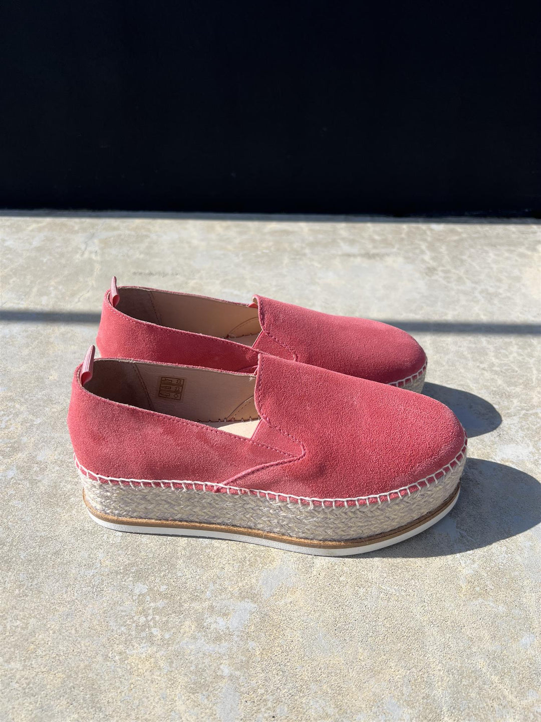 Korallrosa espadrille slip-on sko med platåsåle og jutefletting, sidevinkel på steinfliser i sollys