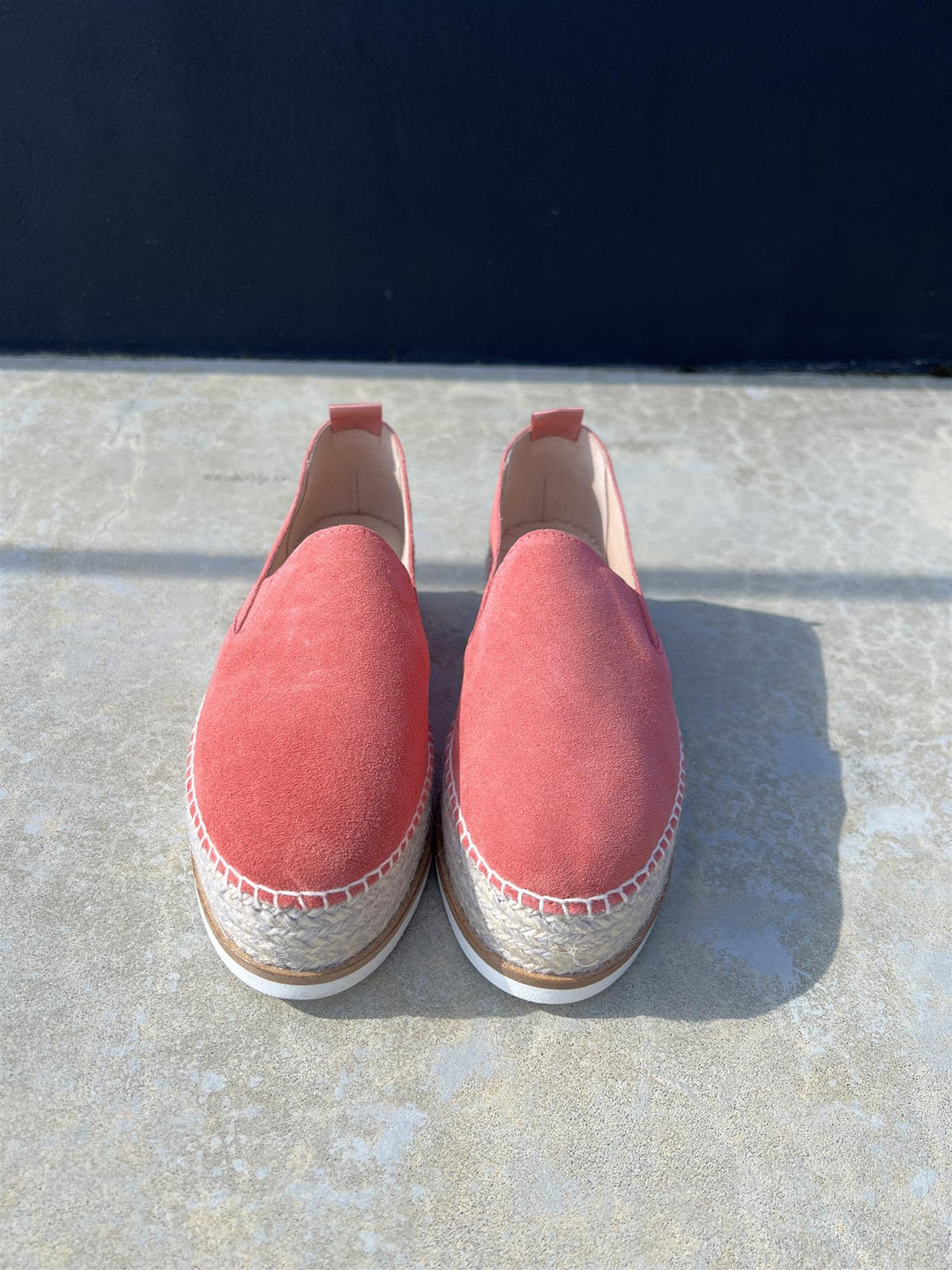 Korall espadrille slip-on sko med platåsåle og jutefletting, frontsett på steinfliser i sollys