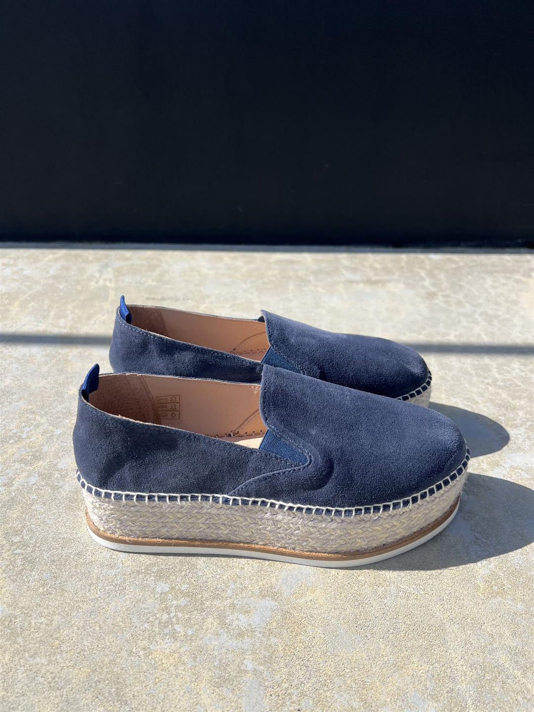 Mørkeblå semsket espadrille med platåsåle i jute, sidevinkel på steinunderlag i sollys