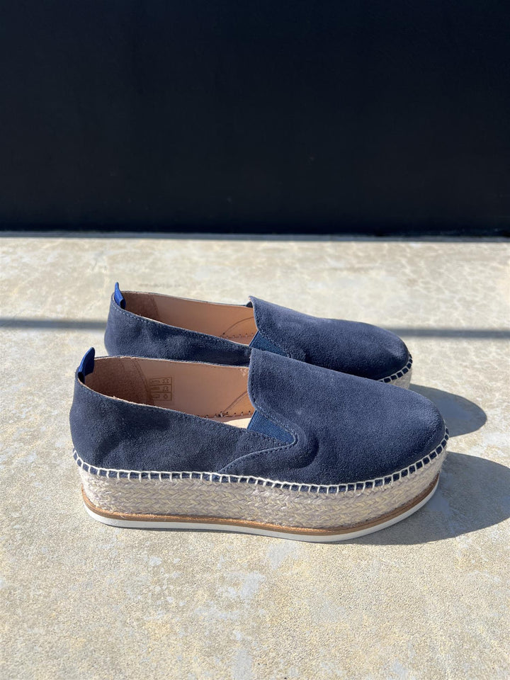 Mørkeblå semsket espadrille med platåsåle i jute, sidevinkel på steinunderlag i sollys