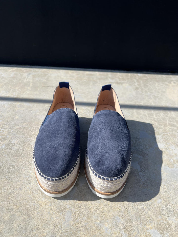 Mørkeblå espadrille slip-on sko med platåsåle, frontsett på steinfliser i sollys