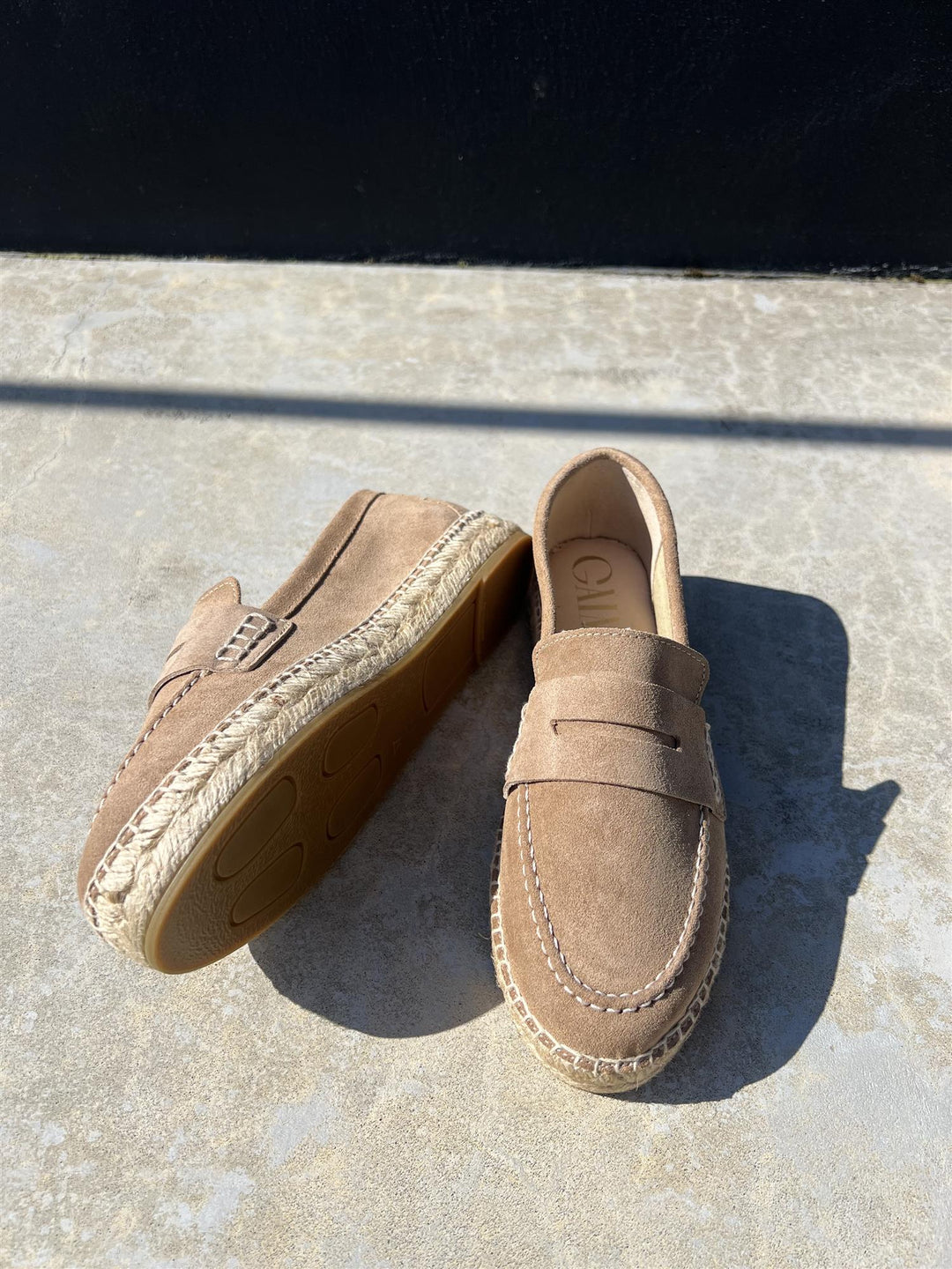 Cuoio loafers med penny-rem og jute-såle, ovenfra på betongflate i sollys