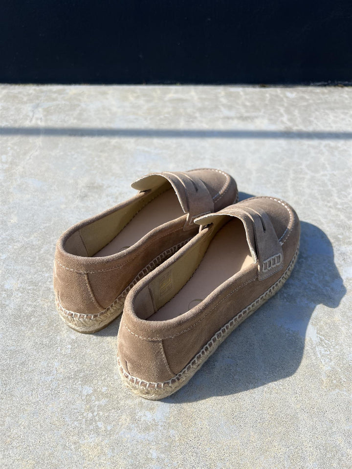 Beige semsket loafers med penny loafer-rem og espadrille-såle, bakside ovenfra på betongflate