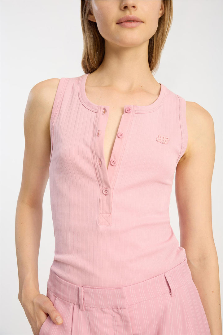 Rosa ermeløs topp med knappelist og brodert logo, frontsett på modell fra brysthøyde