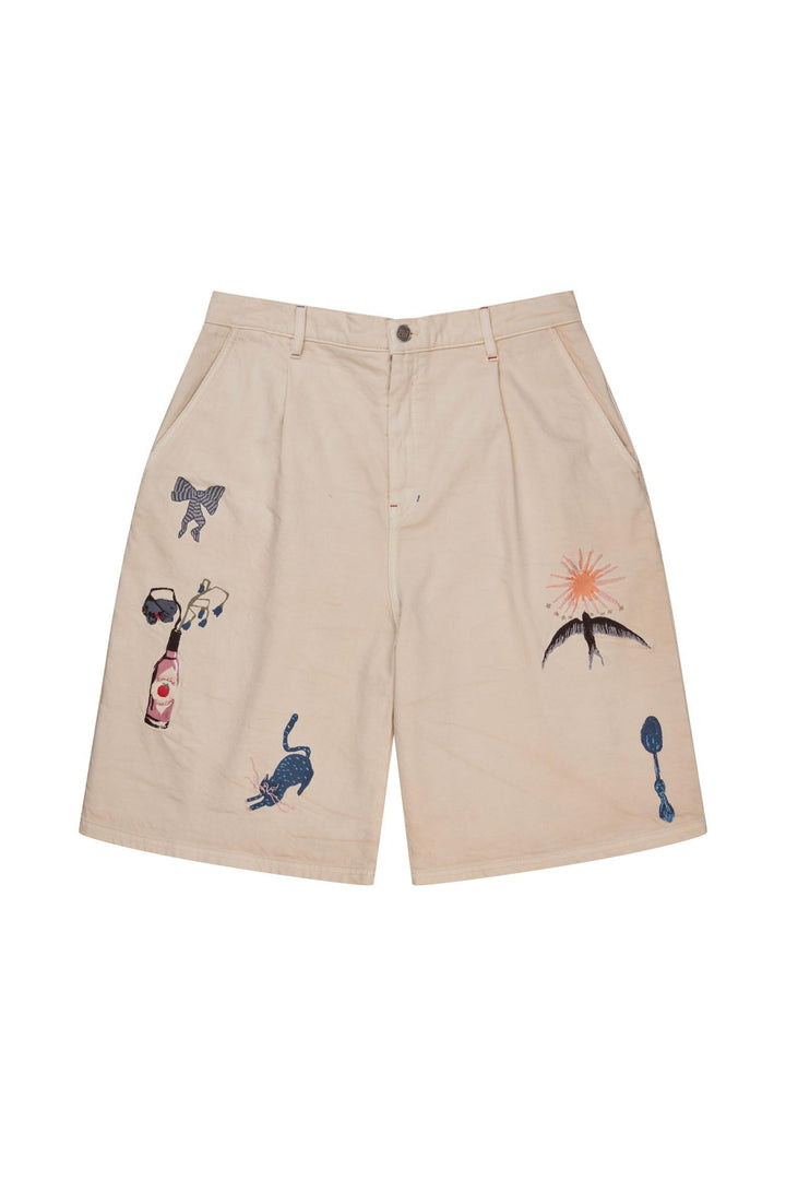 Beige shorts med broderte motiver inkludert palme, katt og flaske, frontsett flat lay på hvit bakgrunn