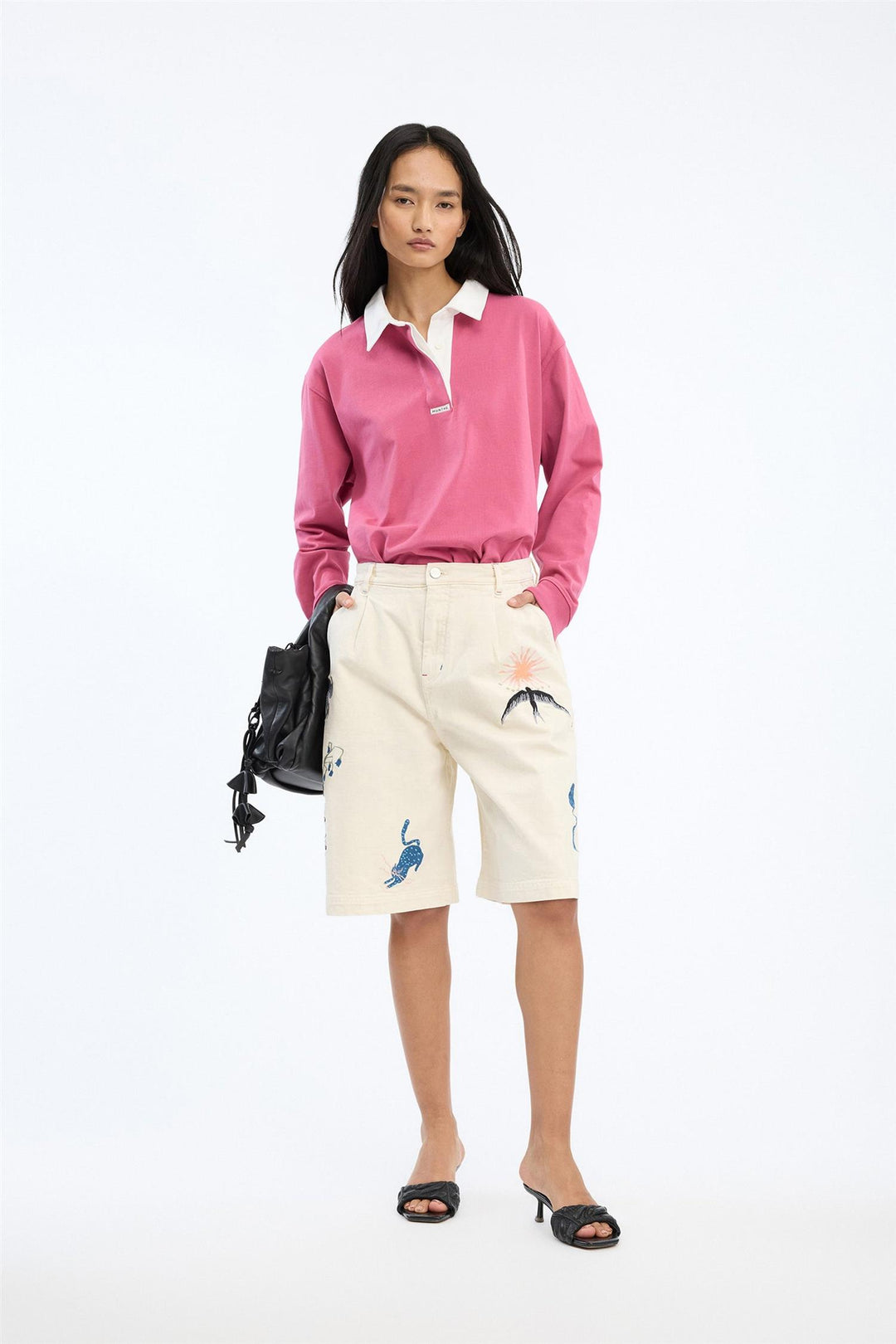 Beige shorts med broderte motiver, frontsett på modell med rosa genser og svart veske