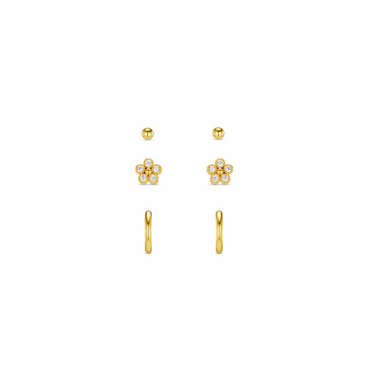 Flat lay av tre par gullbelagte øredobber: ball studs, krystallblomster og micro hoops på hvit bakgrunn