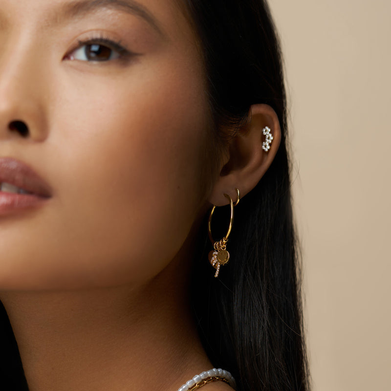 Gullbelagte hoop øredobber med charms på modell, sidevinkel med ear cuff synlig