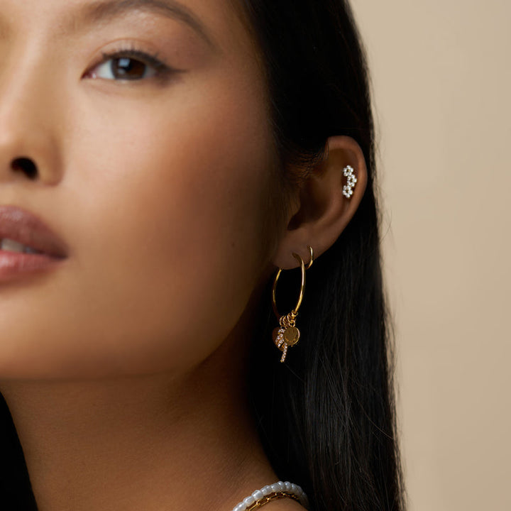 Gullbelagte hoop øredobber med charms på modell, sidevinkel med ear cuff synlig