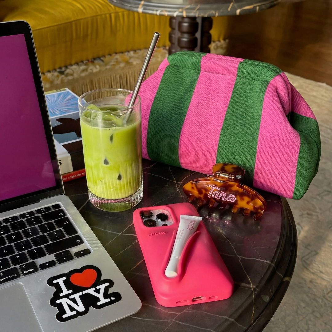 Rosa og grønn stripet clutch-veske med rynket topp i lifestyle-setting med laptop og drink